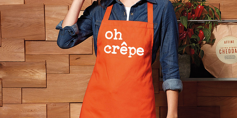 women wearing orange apron with a design on there that says oh crepe, this was created by original monkey