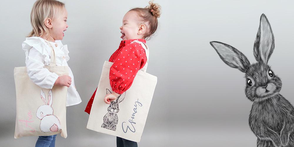 Two little girls holding their personalised easter egg hunt bags
