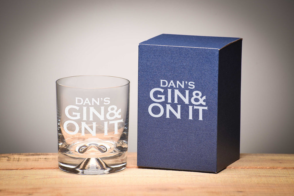 Tumbler short glass on wooden table with personalised message that reads 'Dan's gin and on it' by Original Monkey Gifts with blue gift box.