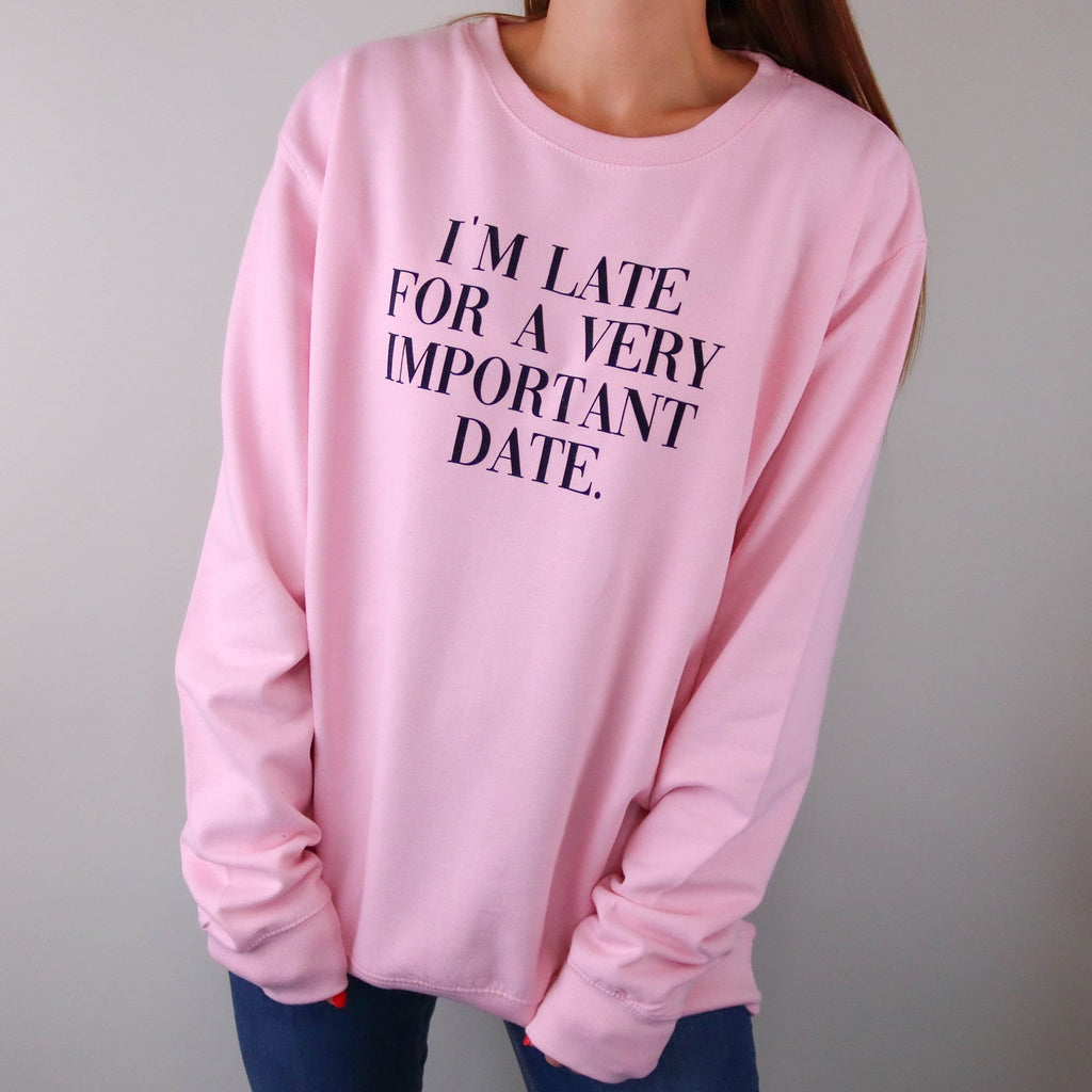 Woman wearing pink sweater with black wording "I'm late for a very important Date" on the front. By Original Monkey Gifts.