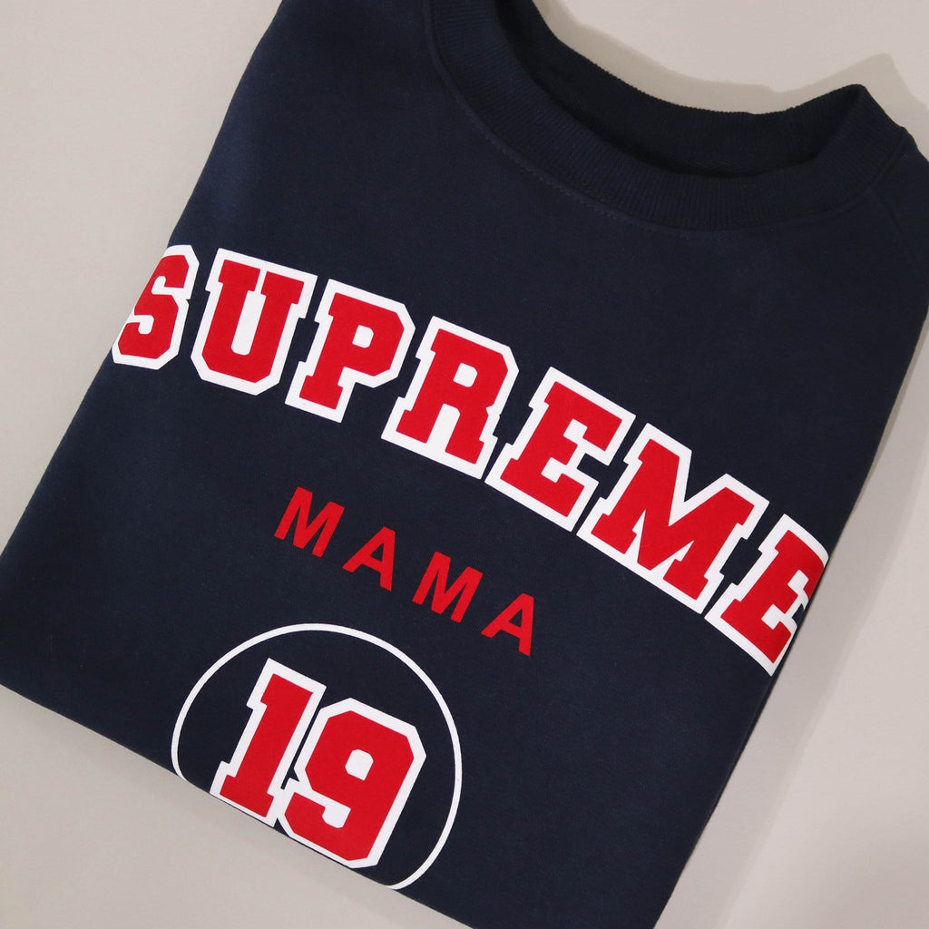 Woman wearing navy blue sweater with personalised Supreme Mama 19 in Red and white and is worn with blue denim jeans. By Original Monkey Gifts.