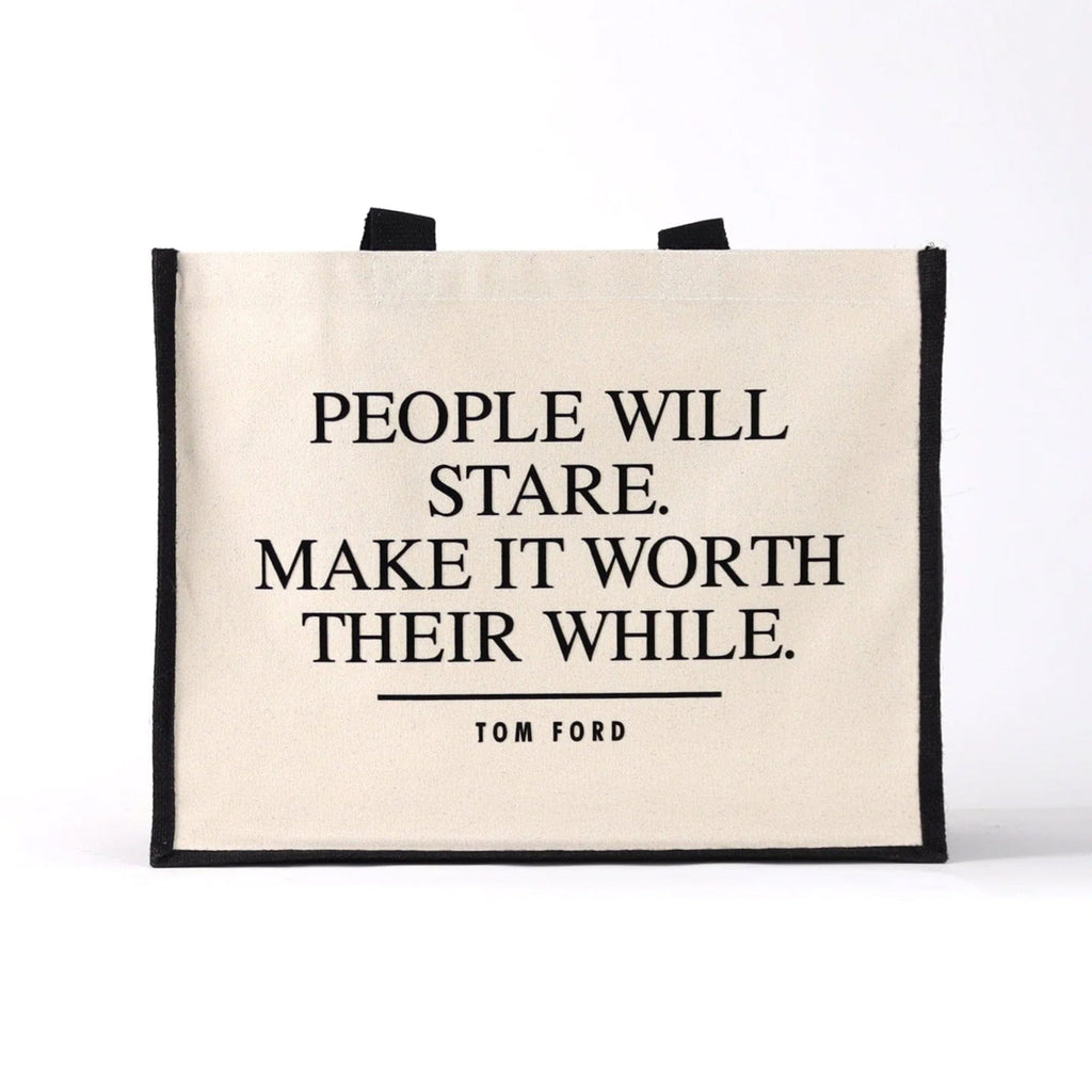 a black cream tote bag with a famous qoute on from a fashion designer, the quote says "people will stare, make it worth their while."