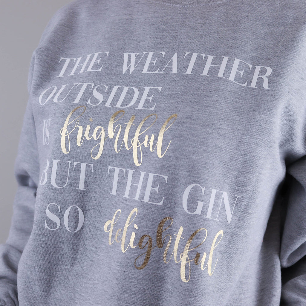 Woman wearing a grey jumper with text reading 'The weather outside is frightful but the gin is so delightful' by Original Monkey Gifts.