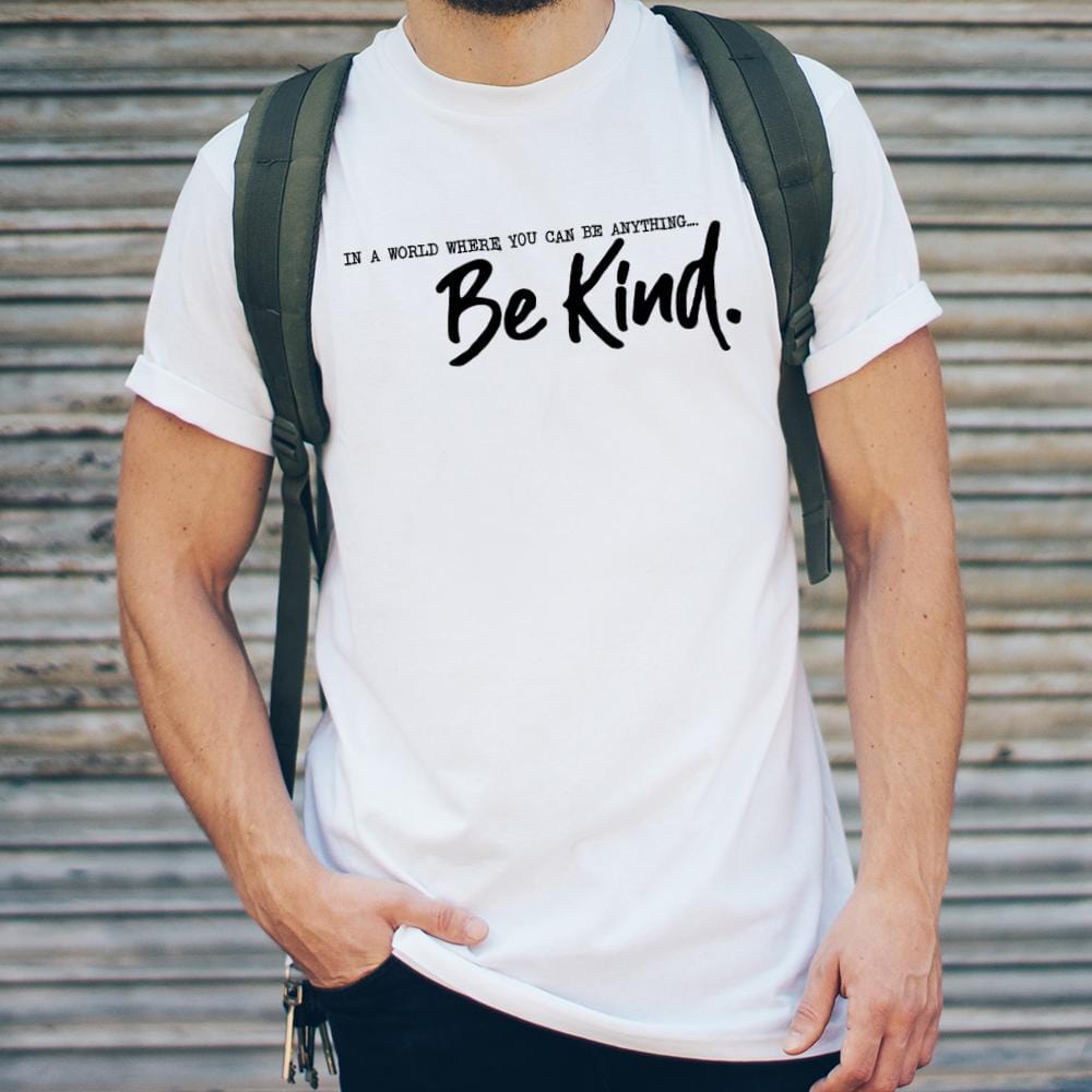 Man wearing a white t shirt with black writing that reads 'in a world where you can be anything... be kind' by Original Monkey Gifts. Man also wears black denim jeans and khaki green rucksack.
