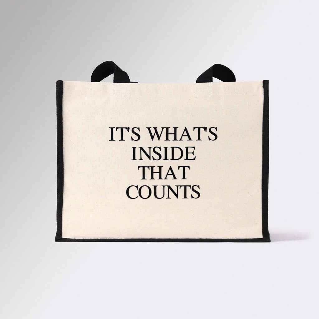 a black and natural tote bag with a quote saying "it's whats inside that counts"