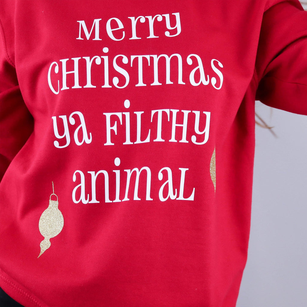 Woman wearing a red jumper with text the reads 'merry christmas ya filthy animal' from Home Alone 2 and gold baubles by Original Monkey Gifts.