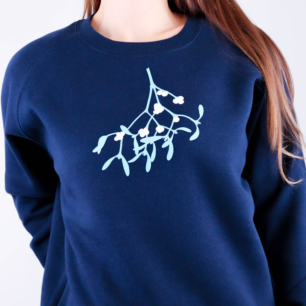 Woman wearing navy jumper with mistletoe design in mint green and white glitter by Original Monkey.