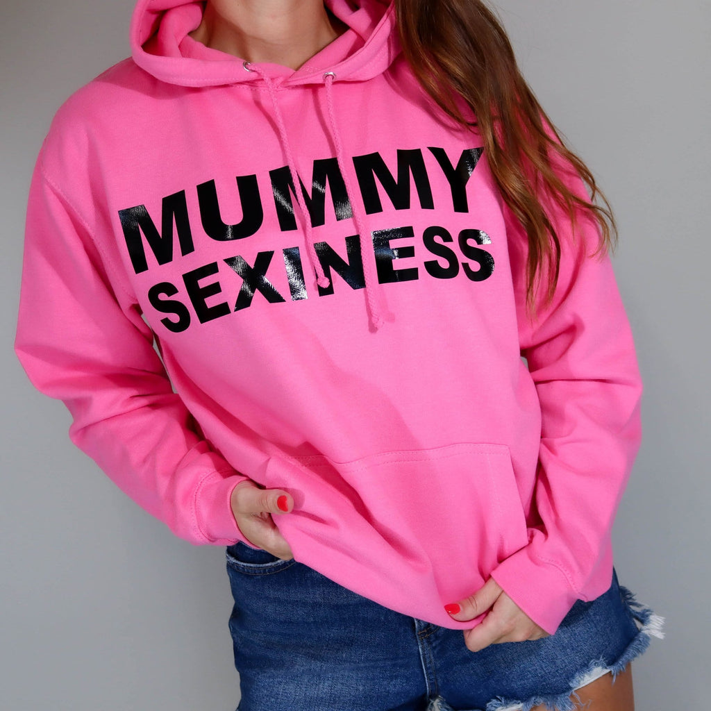 Woman wearing pink hoodie with text that says Mummy sexiness paired with blue denim shorts by Original Monkey Gifts