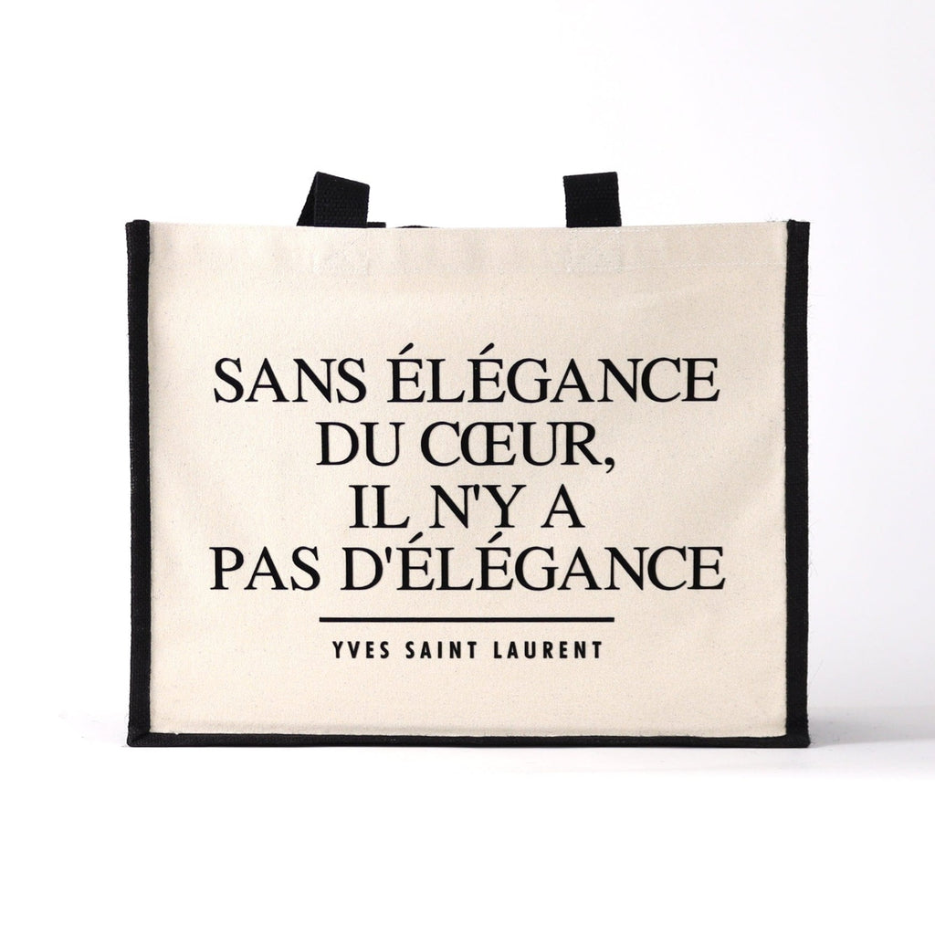 a black and natural tote bag with a fashion designer quote on it saying " without elegance of the heart, there is no elegance"