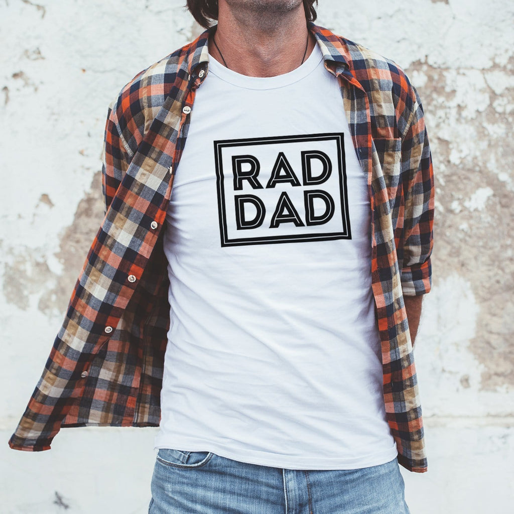 Man wearing a white T shirt with text that reads 'rad dad' in black by Original Monkey Gifts. Man also wears gingham orange shirt and blue denim jeans.