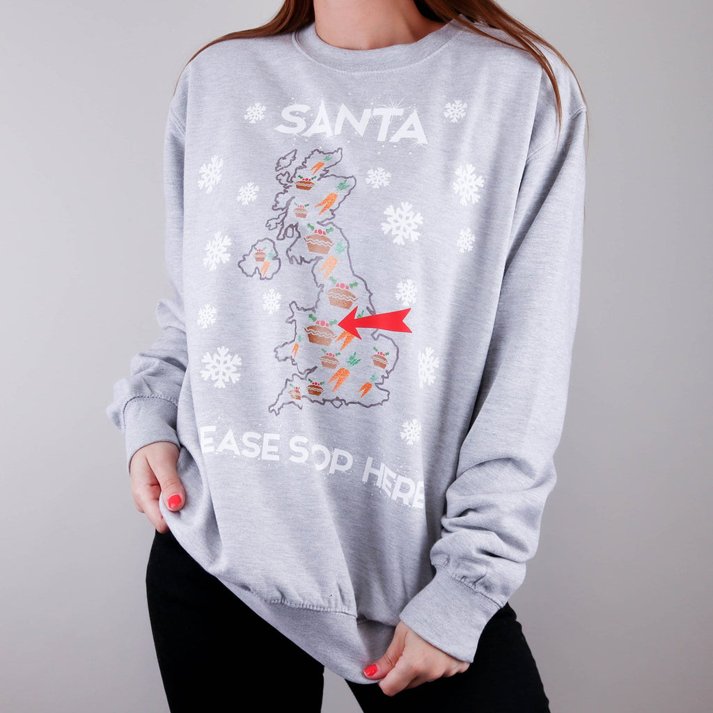 Woman wearing a grey jumper with a map and text reading 'santa please stop here' in white and can be personalised by Original Monkey Gifts. Woman also wearing black denim jeans.