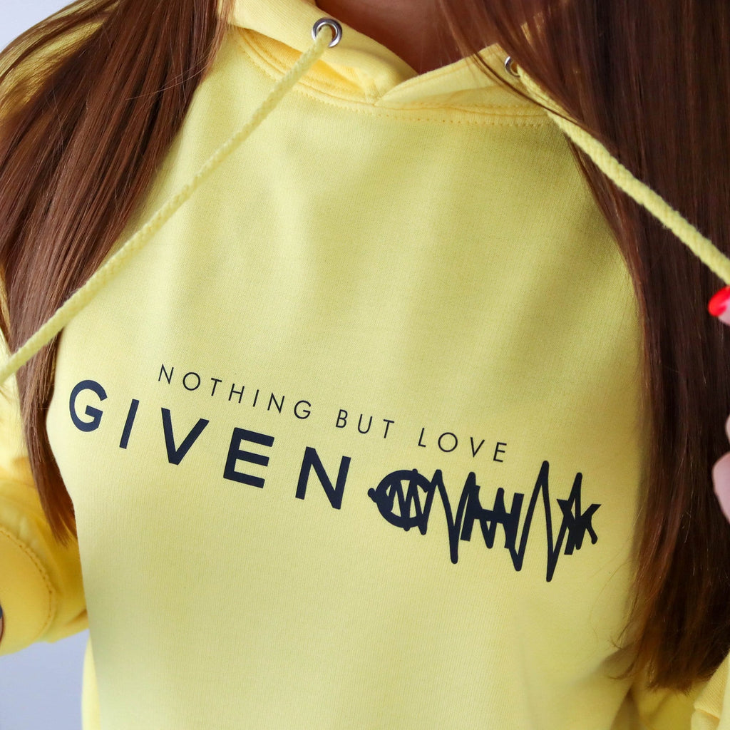 Woman wearing yellow hoodie with text saying nothing but love given paired with blue jeans. By Original Monkey Gifts.